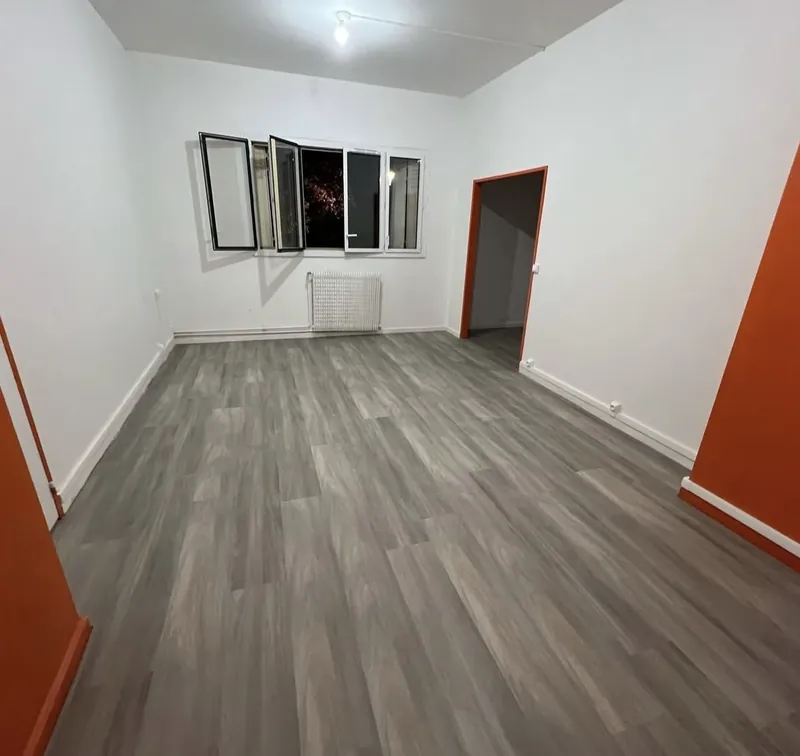 La même pièce livrée : murs blancs, encadrements peints en orange, sol PVC gris