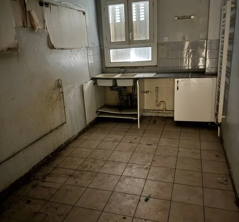 Ancienne cuisine : évier double bac, faïence murale d'origine, sol carrelé encrassé