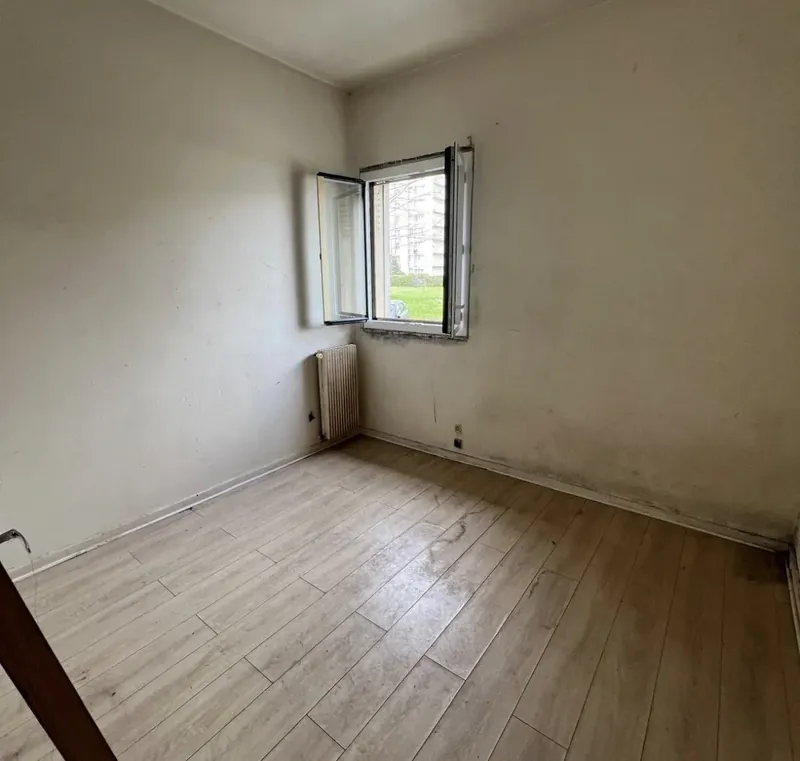 Petite pièce avant travaux : murs tachés, ancienne fenêtre, sol stratifié usé