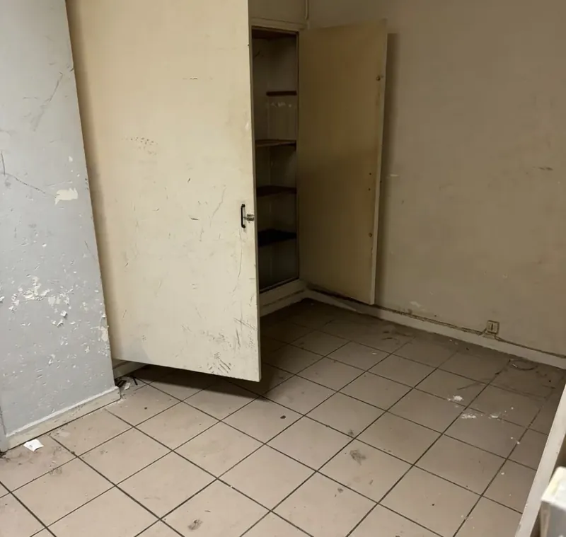 Pièce avec son ancien placard ouvert, sol carrelé et murs abîmés