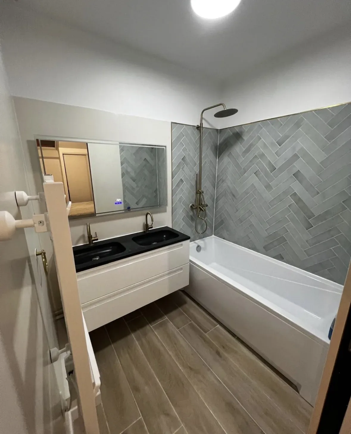 Salle de bain rénovée par ART BÂTIMENT : carrelage chevrons et baignoire neuve