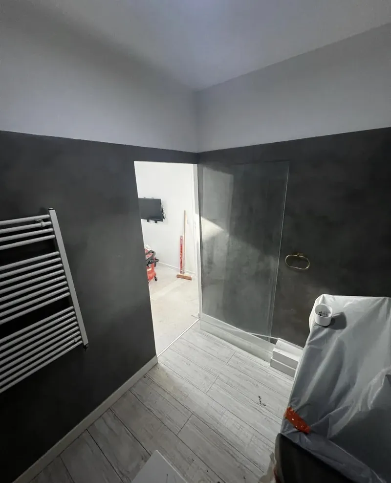 Second angle en cours : murs en sous-couche, sol posé, paroi de douche pas encore fixée
