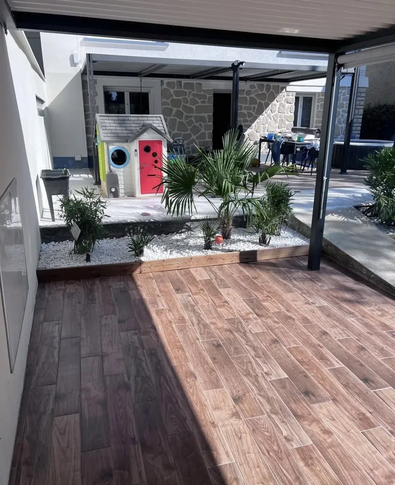 Depuis la terrasse : le massif paysager bordé de bois, et la seconde pergola au fond