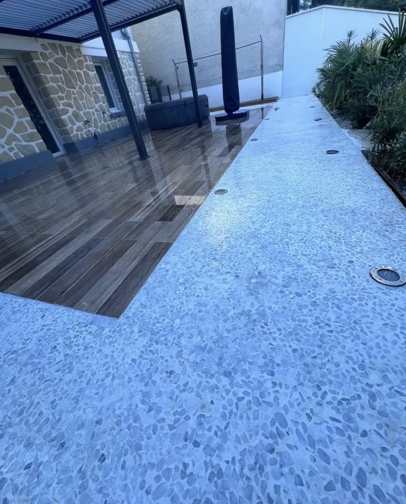La jonction entre le carrelage extérieur et le béton désactivé blanc, spots encastrés alignés dans la bordure